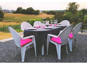 Table dressée sur la terrasse du gîte Au Chant des Roches à Cerfontaine, avec vue sur le jardin verdoyant et les murs en pierre