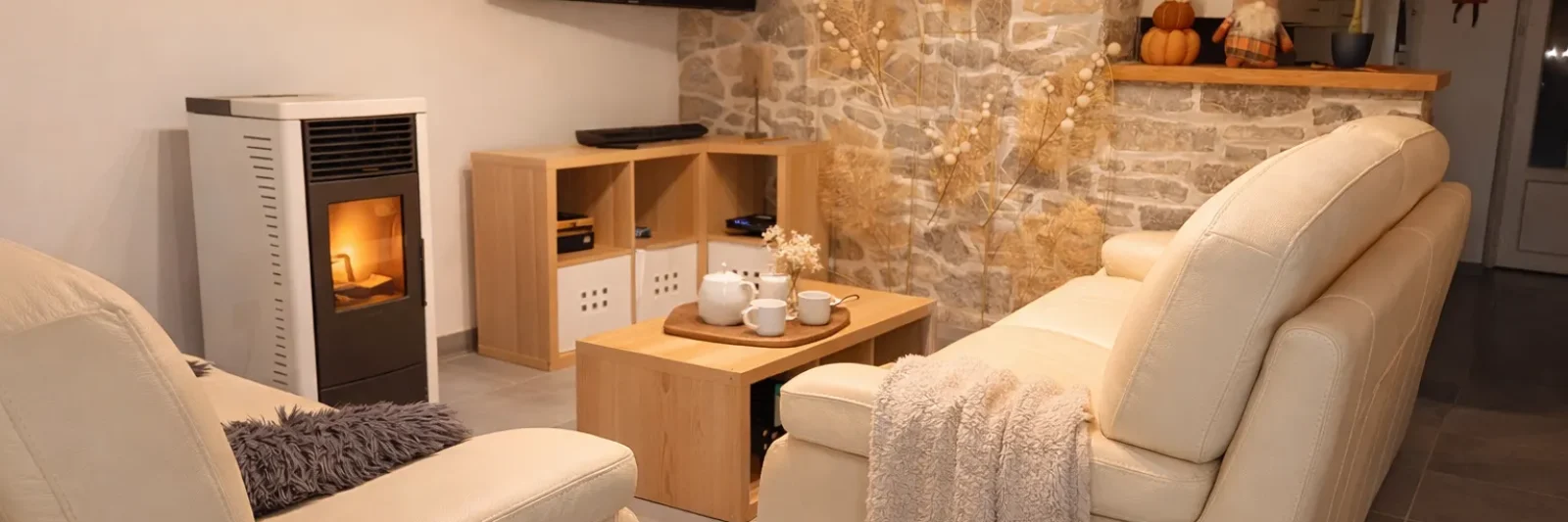 Vue d’ensemble du salon avec mur en pierre et poêle à pellets au gîte Au Chant des Roches